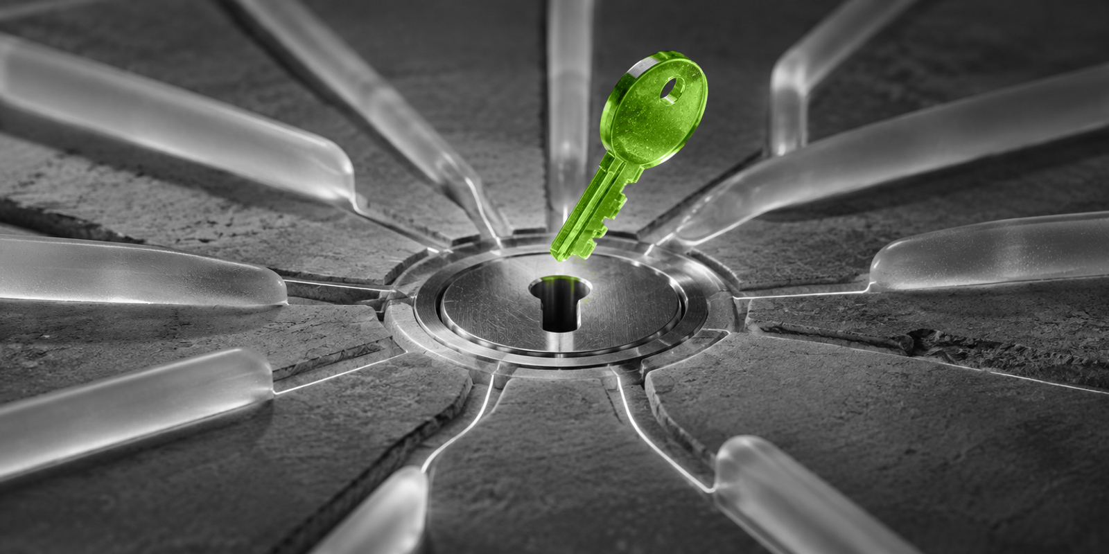 Fotografía conceptual en blanco y negro de una llave translúcida verde suspendida sobre un núcleo circular de metal, con ranuras y canales que convergen hacia el centro sobre una base de piedra mate; la escena sugiere acceso y control reunidos en un único punto de entrada.
